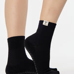 Woman wearing a solid black ankle grip sock with aries zodiac sign embroidered on the side. Made for pilates, barre, yoga, and beyond. 