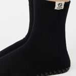 Woman wearing a solid black ankle grip sock with cancer zodiac sign embroidered on the side. Made for pilates, barre, yoga, and beyond. 