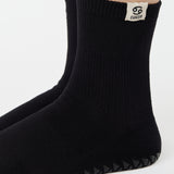 Woman wearing a solid black ankle grip sock with cancer zodiac sign embroidered on the side. Made for pilates, barre, yoga, and beyond. 