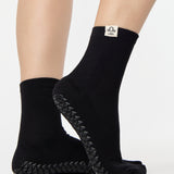 Woman wearing a solid black ankle grip sock with libra zodiac sign embroidered on the side. Made for pilates, barre, yoga, and beyond. 
