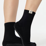 Woman wearing a solid black ankle grip sock with sagittarius zodiac sign embroidered on the side. Made for pilates, barre, yoga, and beyond. 