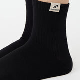 Woman wearing a solid black ankle grip sock with sagittarius zodiac sign embroidered on the side. Made for pilates, barre, yoga, and beyond. 