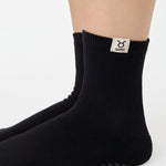 Woman wearing a solid black ankle grip sock with taurus zodiac sign embroidered on the side. Made for pilates, barre, yoga, and beyond. 