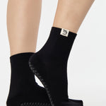 Woman wearing a solid black ankle grip sock with virgo zodiac sign embroidered on the side. Made for pilates, barre, yoga, and beyond. 