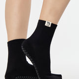 Woman wearing a solid black ankle grip sock with virgo zodiac sign embroidered on the side. Made for pilates, barre, yoga, and beyond. 