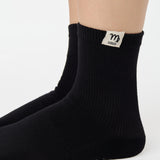 Woman wearing a solid black ankle grip sock with virgo zodiac sign embroidered on the side. Made for pilates, barre, yoga, and beyond. 