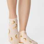 Women wearing an off white full foot grip sock with bananas string of red hearts , made for pilates, barre, yoga, and beyond.