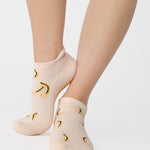 Women wearing an off white full foot grip sock with bananas string of red hearts , made for pilates, barre, yoga, and beyond.