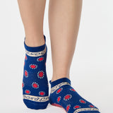 Woman wearing a full foot grip sock that has the design of a classic bandana, in a blue hue with red and white detailing. Made for pilates, barre, yoga and beyond. 