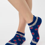 Woman wearing a full foot grip sock that has the design of a classic bandana, in a blue hue with red and white detailing. Made for pilates, barre, yoga and beyond. 
