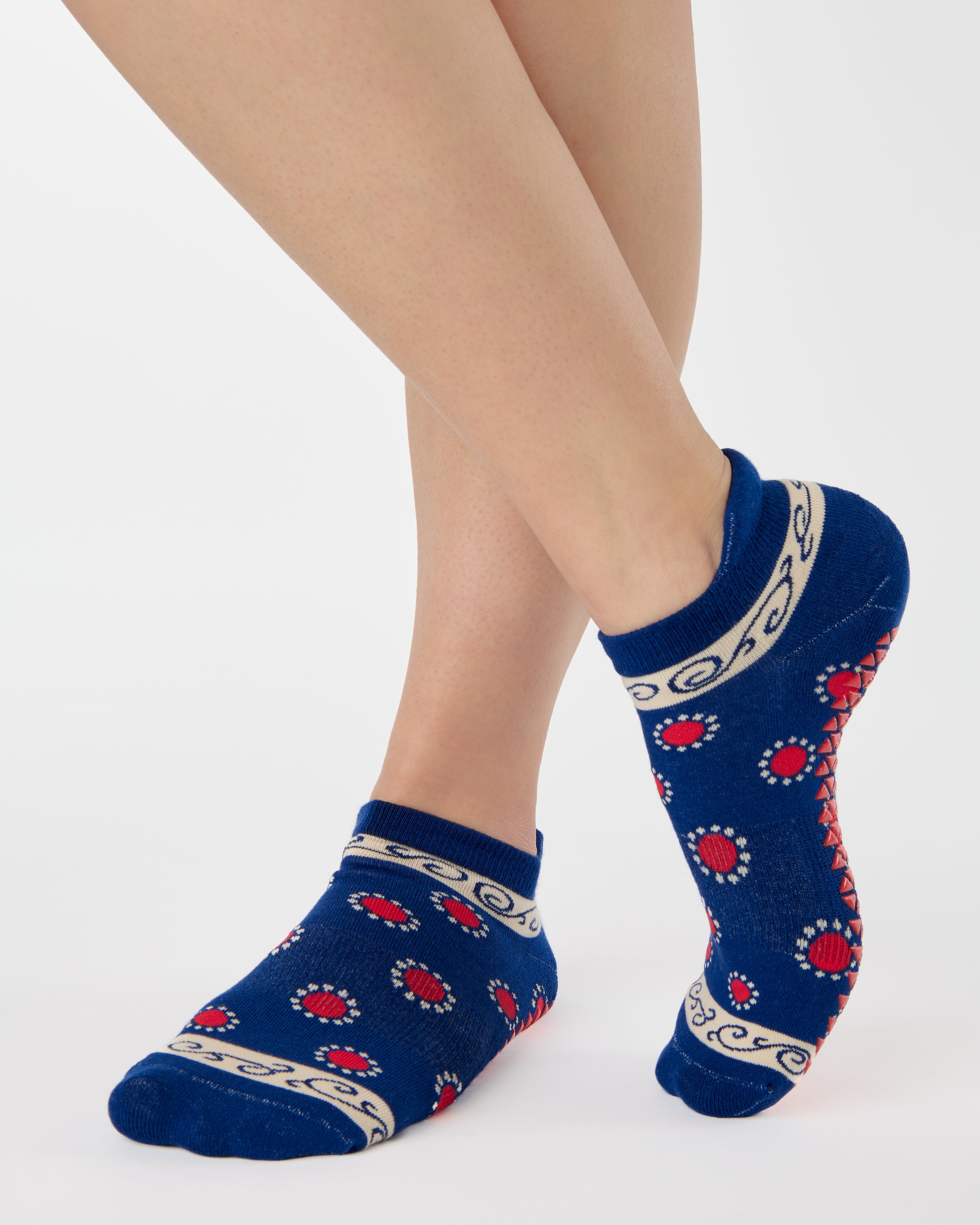 Woman wearing a full foot grip sock that has the design of a classic bandana, in a blue hue with red and white detailing. Made for pilates, barre, yoga and beyond. 