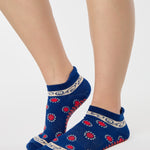 Woman wearing a full foot grip sock that has the design of a classic bandana, in a blue hue with red and white detailing. Made for pilates, barre, yoga and beyond. 