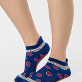 Woman wearing a full foot grip sock that has the design of a classic bandana, in a blue hue with red and white detailing. Made for pilates, barre, yoga and beyond. 