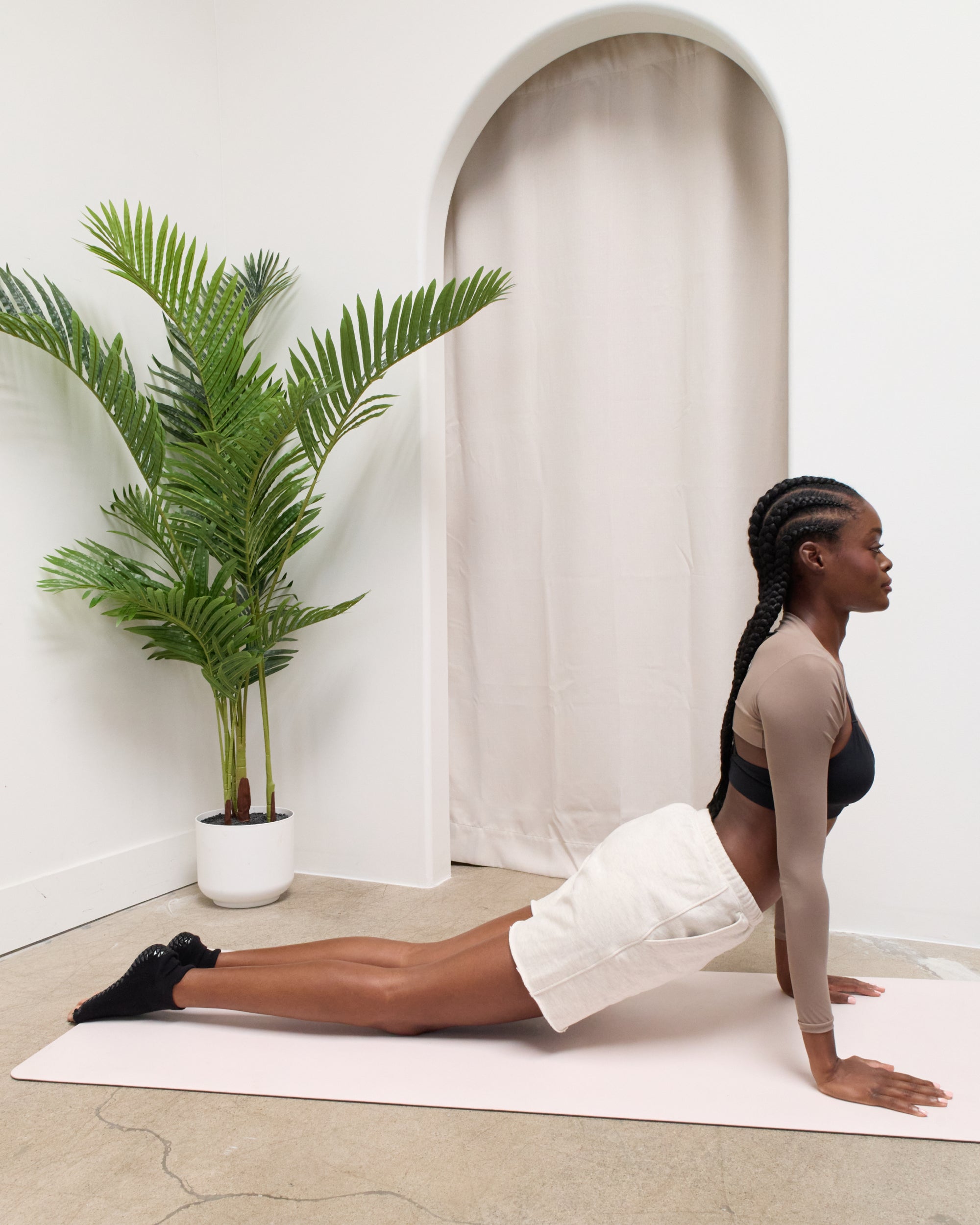 Women on a yoga mat wearing a solid black full foot 5 toeless grip socks, made for pilates, barre, yoga, and beyond.