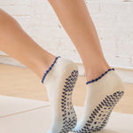 Women on a yoga mat wearing an ombre white into light blue full foot grip sock with a navy blue ruffle cuff and inhale and exhale written on the top of the toes, made for pilates, barre, yoga, and beyond.