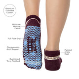 Woman wearing a full foot grip sock that has the design of a classic bandana, in the hues brown cherry and blue and beige detailing. Made for pilates, barre, yoga and beyond. With the product features listed.