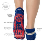 Woman wearing a full foot grip sock that has the design of a classic bandana, in a blue hue with red and white detailing. Made for pilates, barre, yoga and beyond. With all the product features listed.