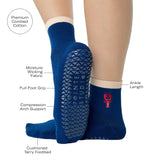 Woman wearing a solid navy blue ankle grip sock with a beige solid cuff and a red lobster embroidered on the ankle. Made for pilates, barre, yoga, and beyond. With a list of all the product details listed. 