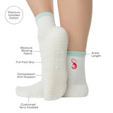 Woman wearing a solid white ankle grip sock with a light blue solid cuff and a red shrimp embroidered on the ankle. Made for pilates, barre, yoga, and beyond. With a list of all of the product features.