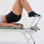Woman on a reformer wearing a black full foot grip sock with woven suns, cacti, and snakes. Made for pilates, barre, yoga, and beyond. 