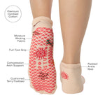Woman wearing a beige full foot grip sock with woven suns, cacti, and snakes. Made for pilates, barre, yoga, and beyond. With the product features listed.