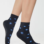 Women wearing a black ankle grip sock with evil eye pattern all around, made for pilates, barre, yoga, and beyond.