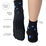 Women wearing a black ankle grip sock with evil eye pattern all around, made for pilates, barre, yoga, and beyond with the product features listed.