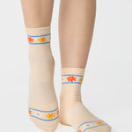 Women wearing an off white ivory ankle grip sock with a flower pattern wrapped around the ankle cuff and toes, made for pilates, barre, yoga, and beyond.