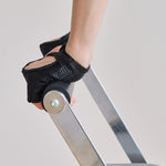 Woman wearing a pair of black grip gloves that has an opening for the fingers a breathable open back design, made for the studio and strength training. 