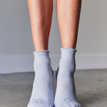 Women wearing light blue ankle grip socks with blue happy face for Pilates, Barre, Yoga, and beyond. 