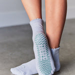 Women wearing light blue ankle grip socks with blue happy face for Pilates, Barre, Yoga, and beyond. 
