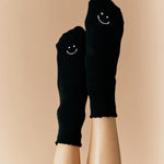 Women wearing black ankle grip socks with white happy face for Pilates, Barre, Yoga, and beyond. 