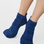 Women wearing blue smiley face patterned grip socks made for Pilates, Barre, Yoga, and beyond. 