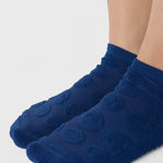 Women wearing blue smiley face patterned grip socks made for Pilates, Barre, Yoga, and beyond. 