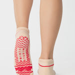 Women wearing a solid off white full foot grip sock with a string of red hearts , made for pilates, barre, yoga, and beyond.