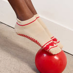 Women wearing a solid off white full foot grip sock with a string of red hearts , made for pilates, barre, yoga, and beyond.