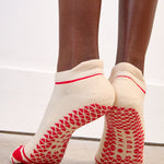 Women wearing a solid off white full foot grip sock with a string of red hearts , made for pilates, barre, yoga, and beyond.