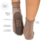 Women wearing brown ankle grip socks with black happy face for Pilates, Barre, Yoga, and beyond with all features listed.