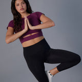 Woman practicing yoga wearing a white sold color full foot grip sock with crows circling the cuff. Made for pilates, barre, yoga, and beyond.