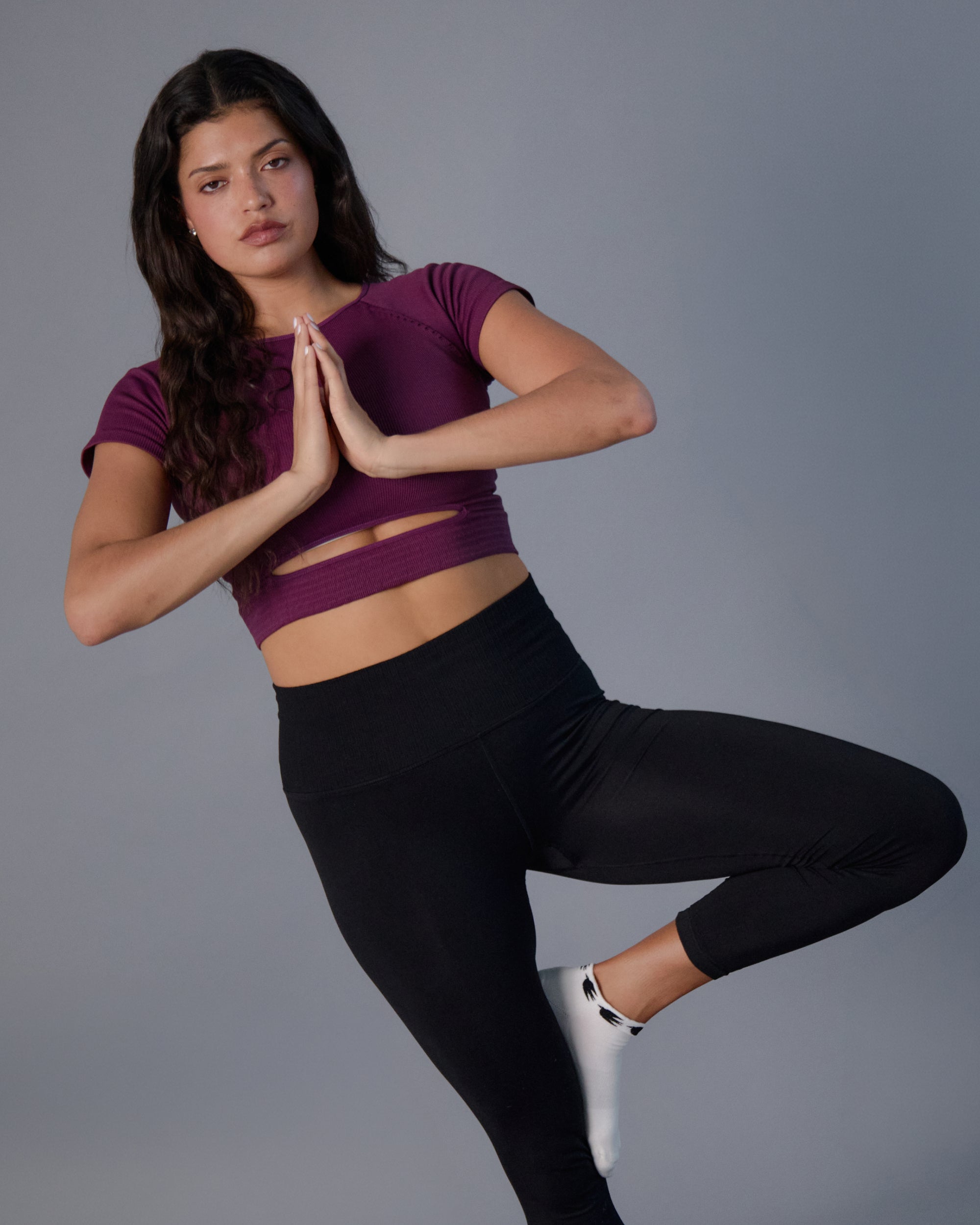 Woman practicing yoga wearing a white sold color full foot grip sock with crows circling the cuff. Made for pilates, barre, yoga, and beyond.