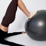 Woman wearing a beige sold color full foot grip sock with snails circling the cuff. Made for pilates, barre, yoga, and beyond.