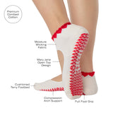 Woman wearing solid white strap grip sock with red heart wrapping around the scalloped cuff, made for pilates, barre, yoga, and beyond. With all the product features listed.