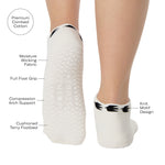 Woman wearing a white sold color full foot grip sock with crows circling the cuff. Made for pilates, barre, yoga, and beyond. With all the product features listed.