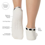Woman wearing a white sold color full foot grip sock with crows circling the cuff. Made for pilates, barre, yoga, and beyond. With all the product features listed.