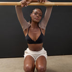 Woman wearing a solid black strap grip sock, made for pilates, barre, yoga, and beyond. 