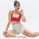 Women wearing a off white ankle grip sock with a red heart motif on the top made for Pilates, Barre, Yoga, and beyond. 