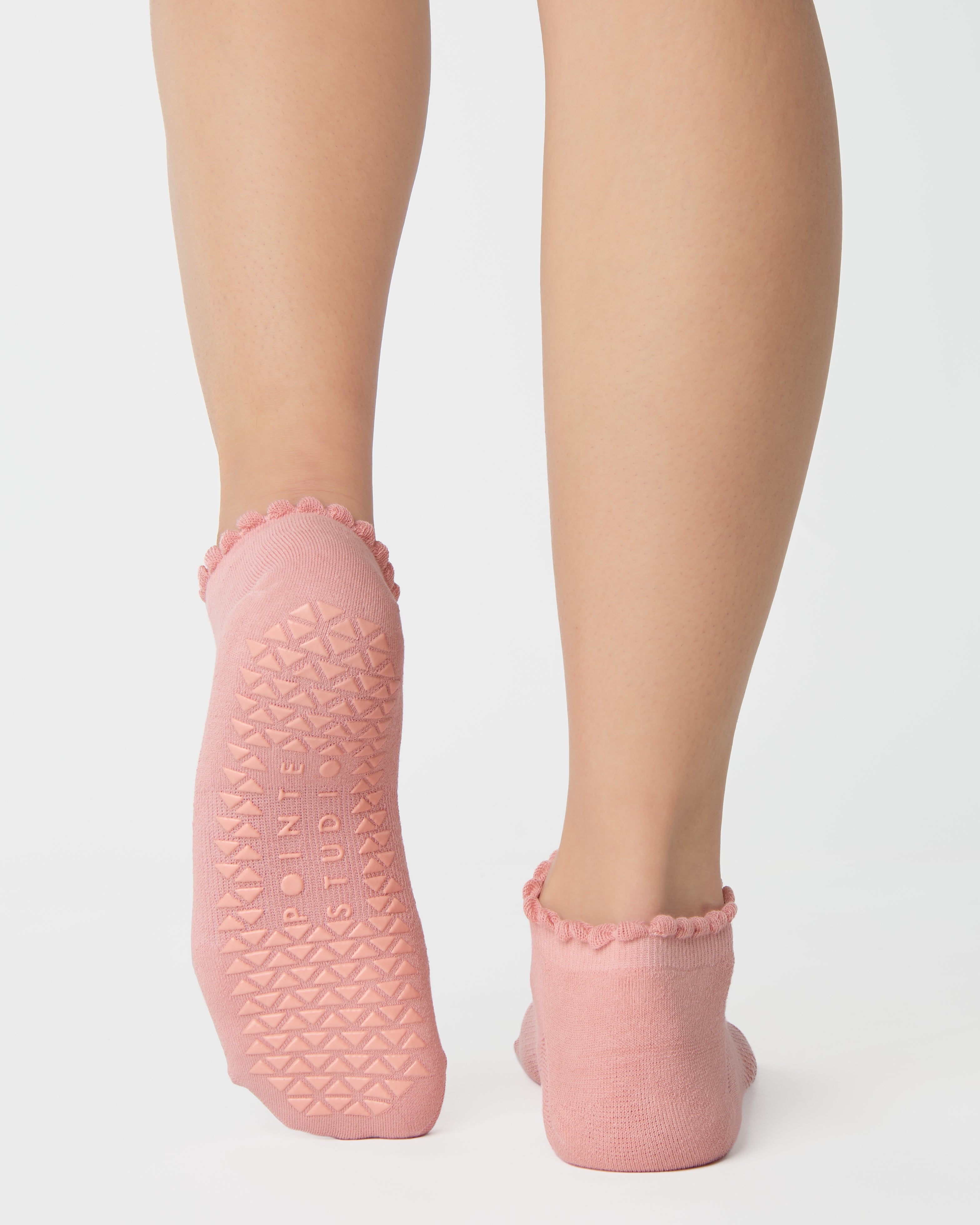 Women wearing a coral pink full foot grip sock with a dark brown heart motif on the top made for Pilates, Barre, Yoga, and beyond. 