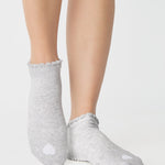 Women wearing a heather grey full foot grip sock with a white heart motif on the top made for Pilates, Barre, Yoga, and beyond. 