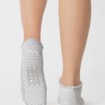 Women wearing a heather grey full foot grip sock with a white heart motif on the top made for Pilates, Barre, Yoga, and beyond. 