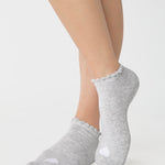 Women wearing a heather grey full foot grip sock with a white heart motif on the top made for Pilates, Barre, Yoga, and beyond. 